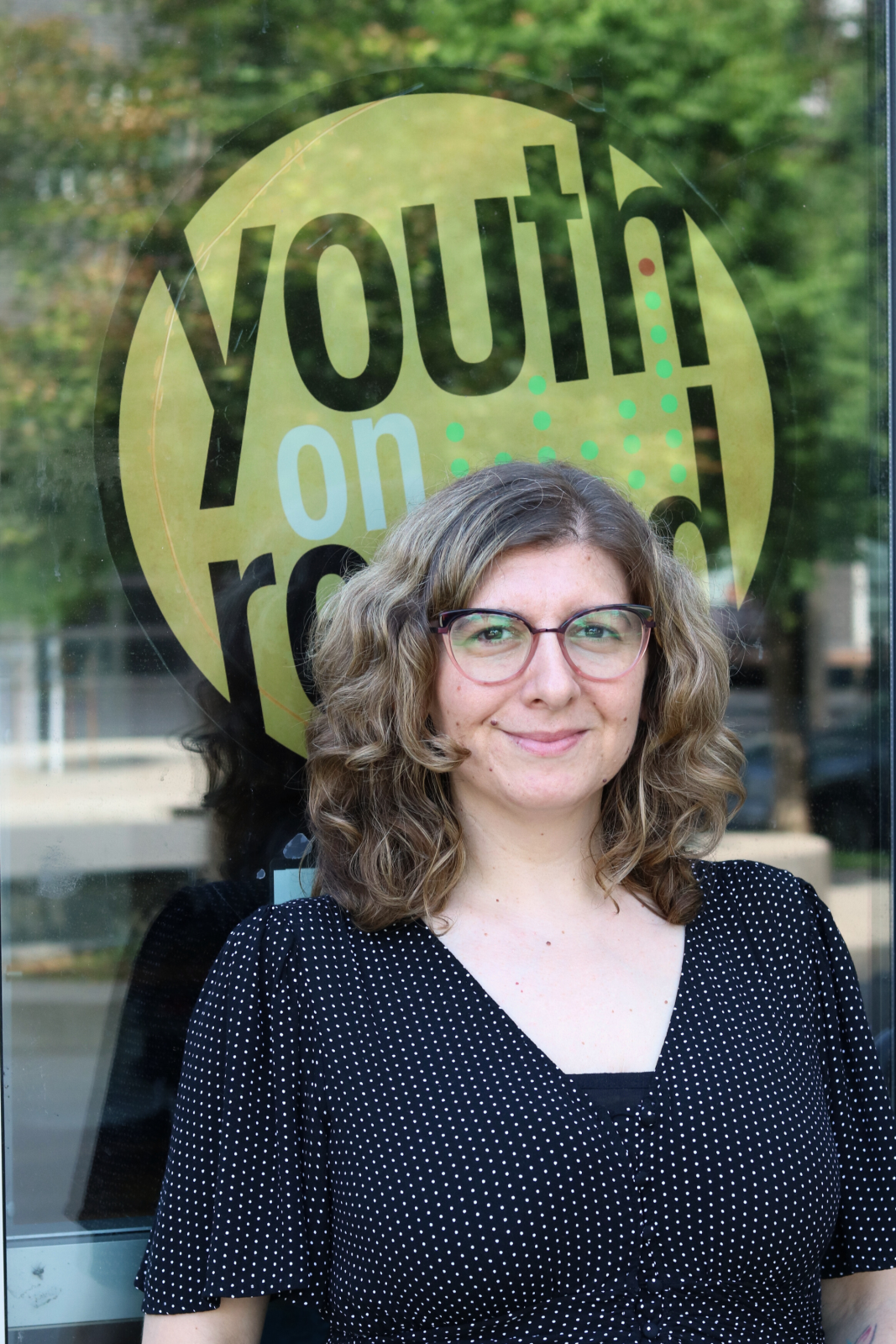 lindsay smiles in front of yor logo