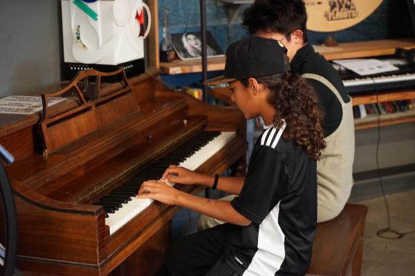 A middle school camper plays piano