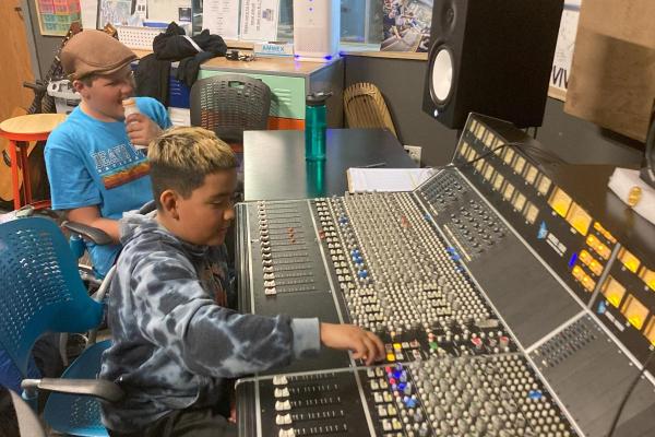 Two podcast campers mix audio at the sound board