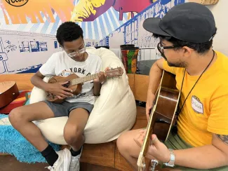 Caleb teaches a middle school camper guitar